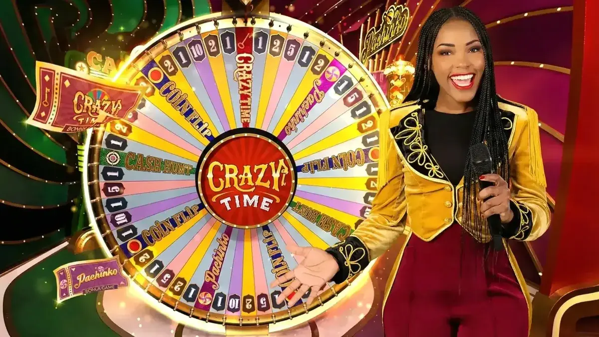 Crazy Time host standing in the live studio beside the money wheel